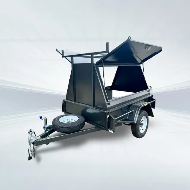 Studio side angled view of black 7x4 tradesman trailer with flip-top canopy open on white background.