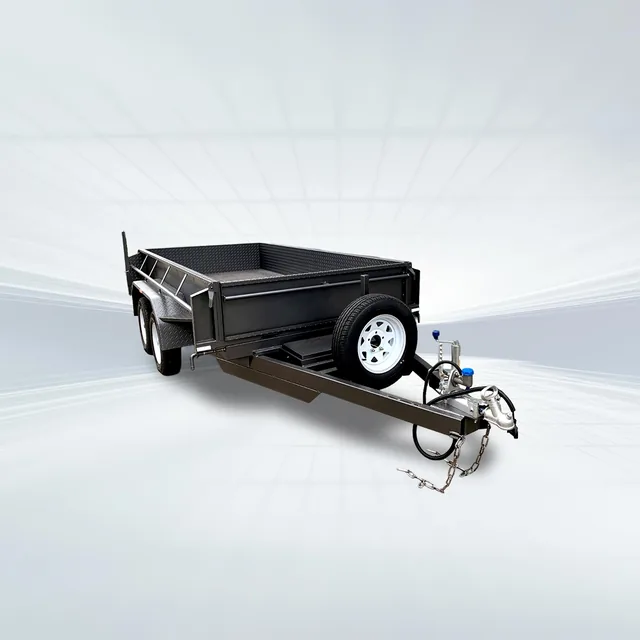Studio side angled view of black 8x5 tipper trailer with machinery upgrade and slide-in ramps on white background.